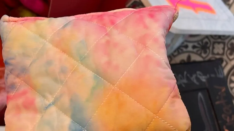 Multicolored pillow with quilting pattern indoors.