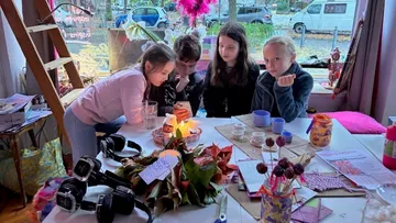 Children sitting around a table, looking at a phone.