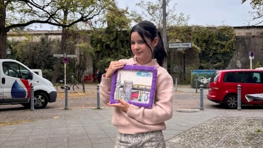 Person holding art on a city street.