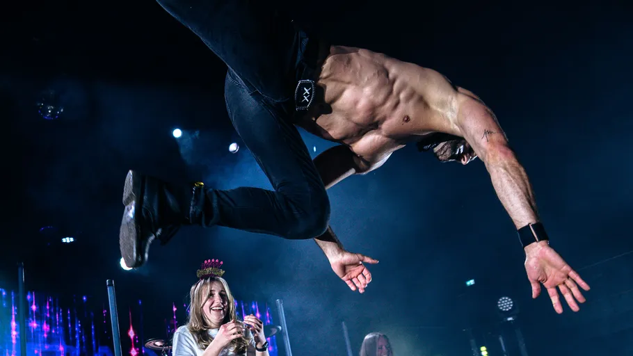 Shirtless man performing a flip on stage.