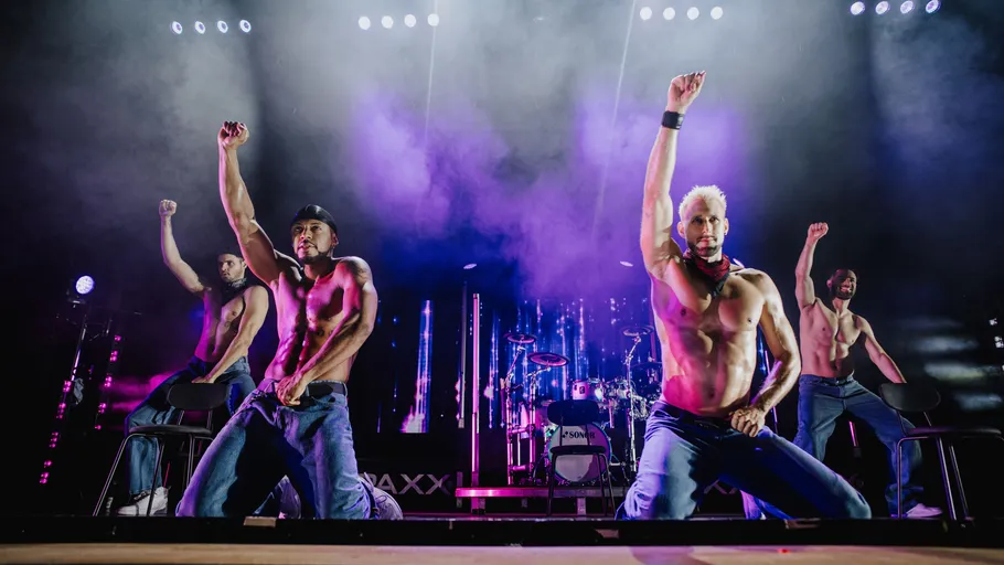 Shirtless dancers perform energetically on stage.