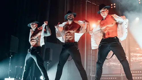 Drei männliche Tänzer auf der Bühne.