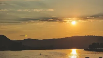 Sunset over hills and river landscape.
