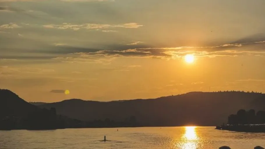 Sonnenuntergang über Hügeln und Flusslandschaft.