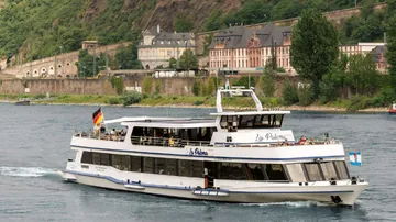 Passenger boat cruising on a river near buildings.