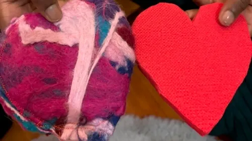 Zwei Hände halten bunte Herzen drinnen.