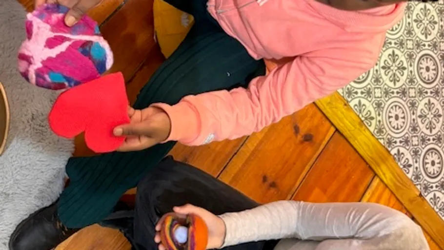 Kinder halten bunte herzförmige Objekte drinnen.