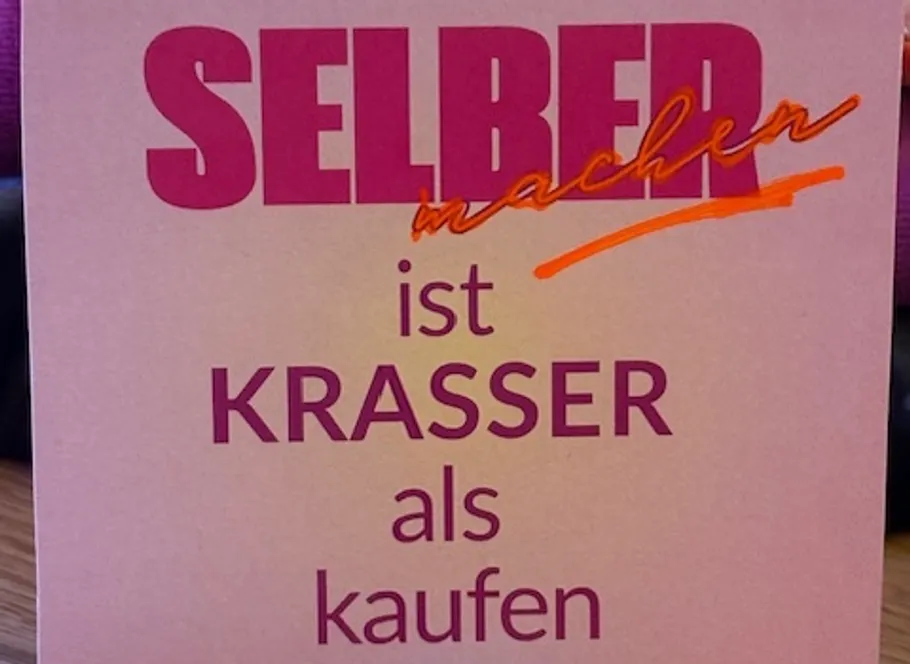 Schild auf Tisch sagt Machen ist krasser als kaufen.
