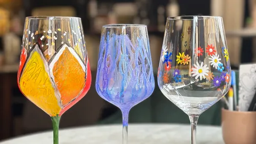 Bunte bemalte Weingläser auf Tisch.