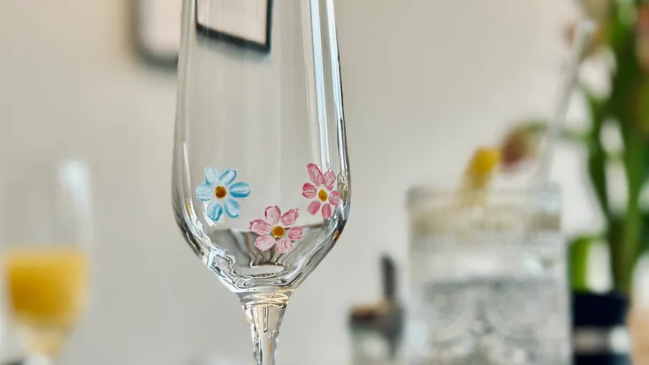 Glas mit Blumendesign auf Tisch.