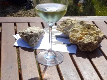 Wine glass stands next to stones on a wooden table.
