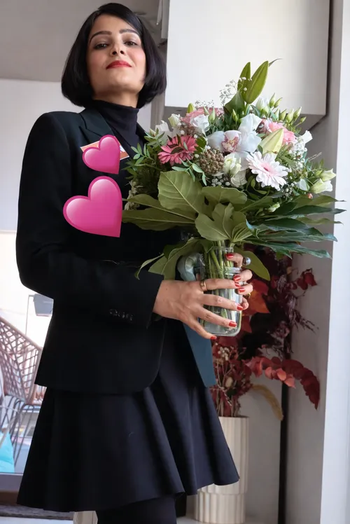 Woman holding a bouquet indoors, pink hearts.