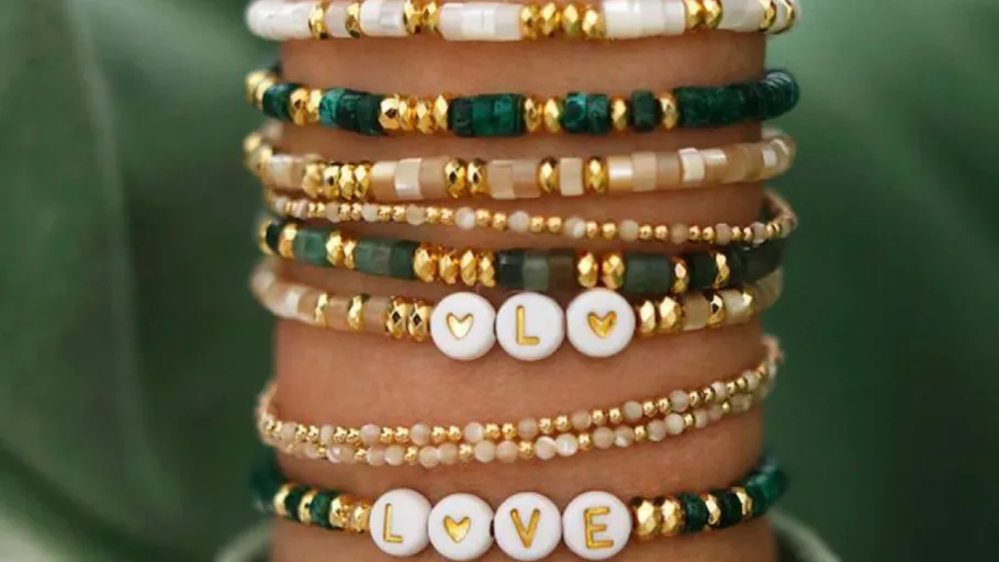 Bunte Perlenarmbänder mit 'LOVE' am Handgelenk.