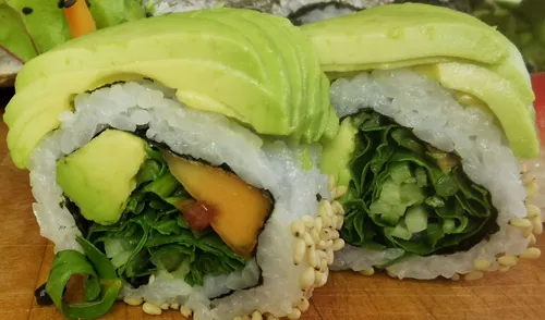 Avocado-überzogene Sushirollen mit Gemüse gefüllt.