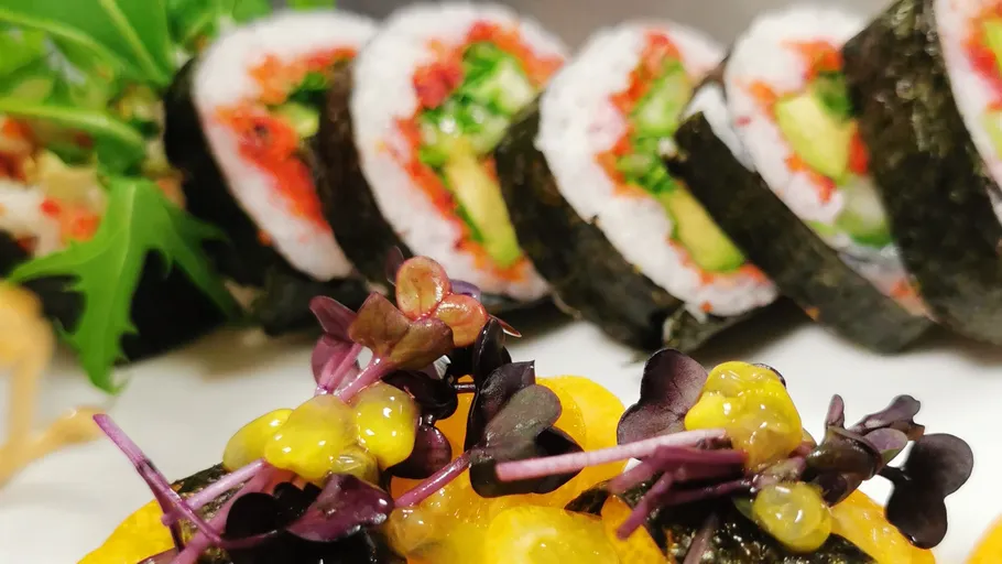 Sushi rolls with vibrant garnishes on plate.