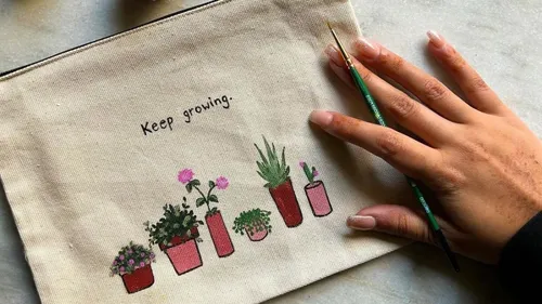 Hand painting plants on fabric pouch.