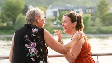 Zwei Personen lachen auf einem Bootsdeck.