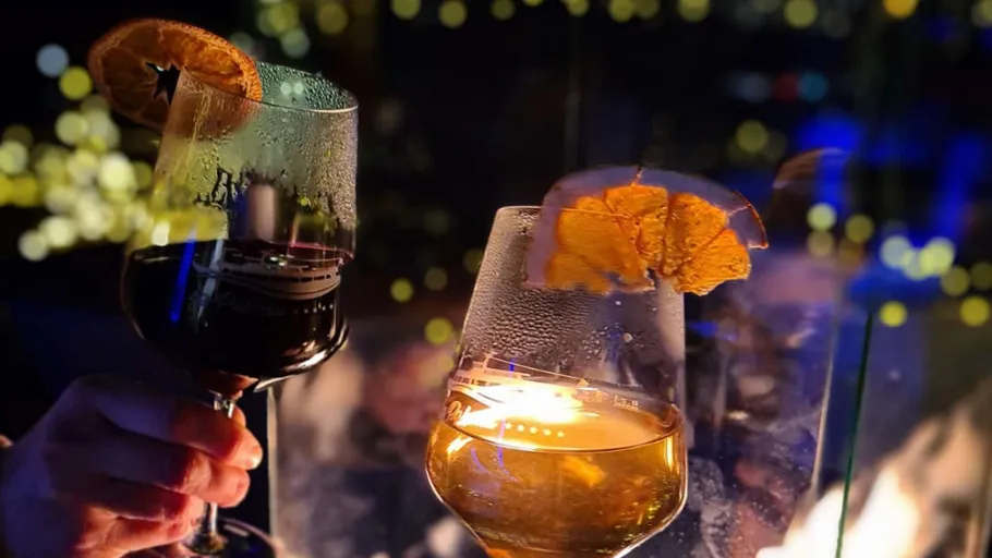 Two glasses toasting against city lights.