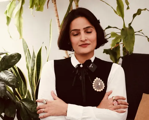 Woman with closed eyes surrounded by plants.