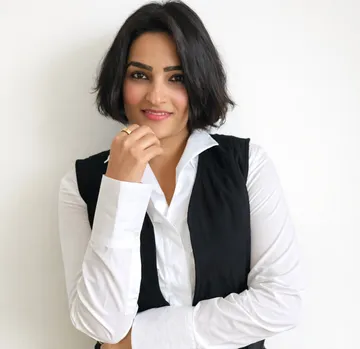 Woman smiling, wearing white shirt, black vest.