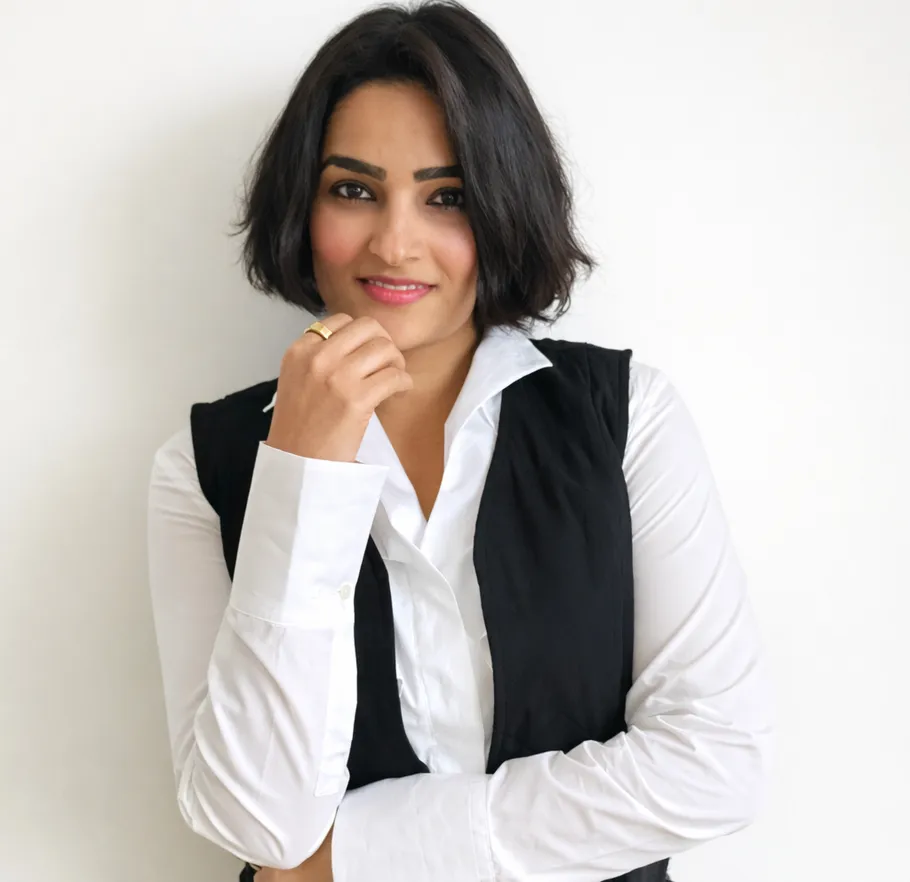Woman smiling, wearing white shirt, black vest.