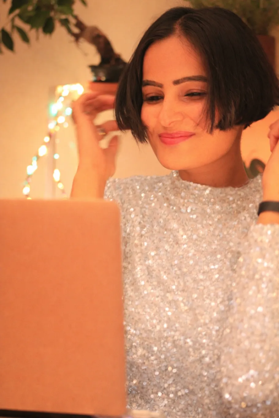 Woman smiling, using a laptop in cozy room.