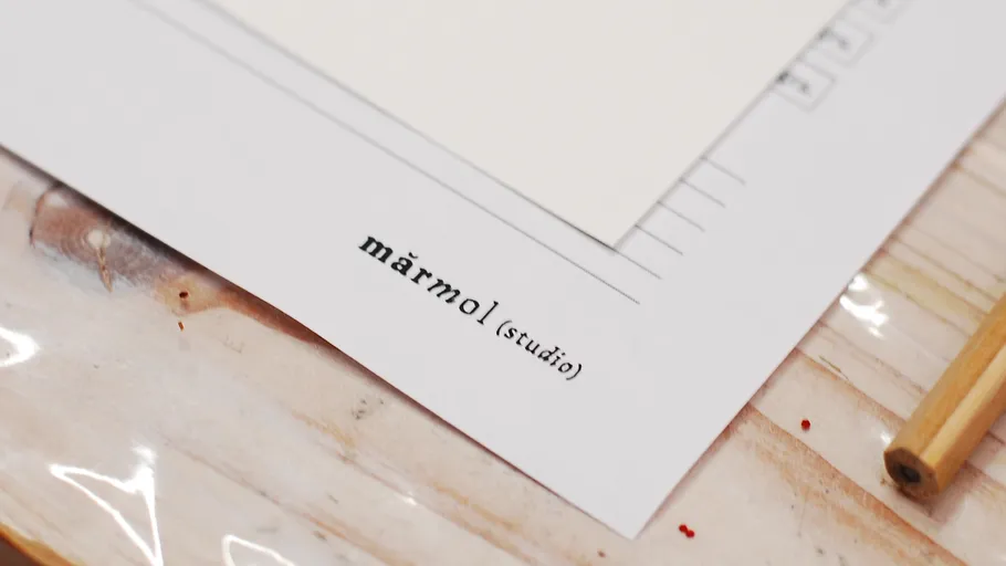 Document with text 'mārmol (studio)' on desk.