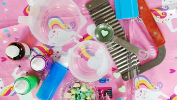 Colorful soap-making supplies on unicorn tablecloth.