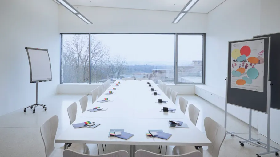 Leerer Konferenzraum mit Stühlen, Fenstern, Tafeln.