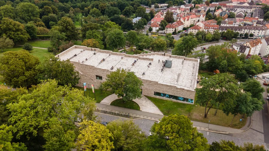 Modern building amidst lush green park and trees.
