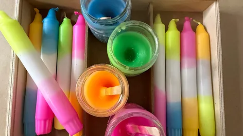 Bunte Kerzen in einer Holzkiste.