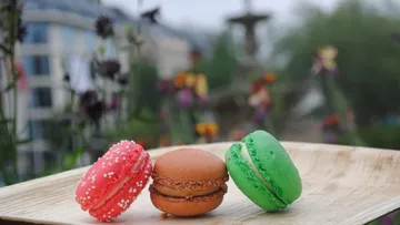 Three macarons on a wooden plate outdoors.
