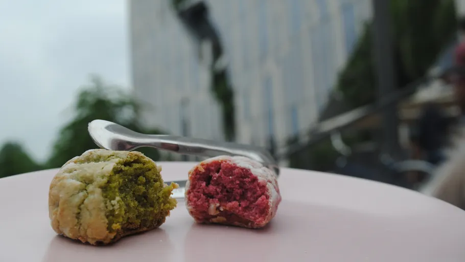 Two colored cookies on a plate outdoors.