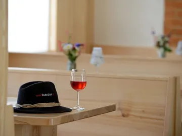 Black hat and wine glass on a wooden tray.