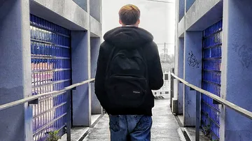 Person mit Rucksack geht durch blauen Korridor.