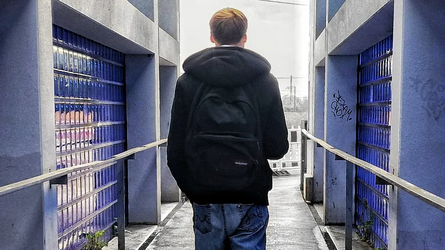 Person with backpack walks through blue corridor.