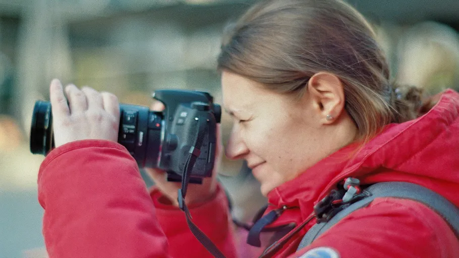 Woman in red jacket photographing outdoors.
