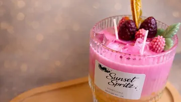 Pink candle in glass with fruit decoration.