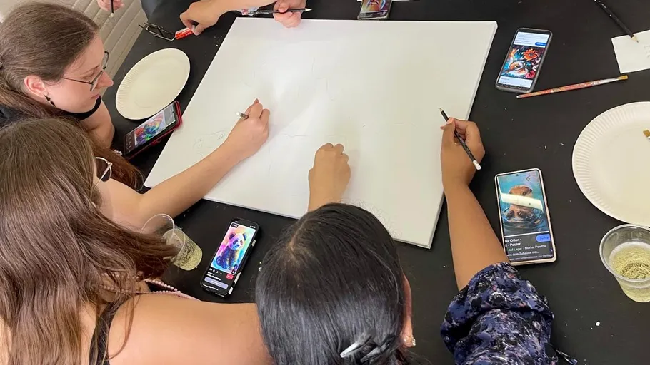People drawing on canvas at a table.