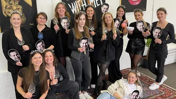 Gruppe von Frauen mit Weingläsern drinnen.