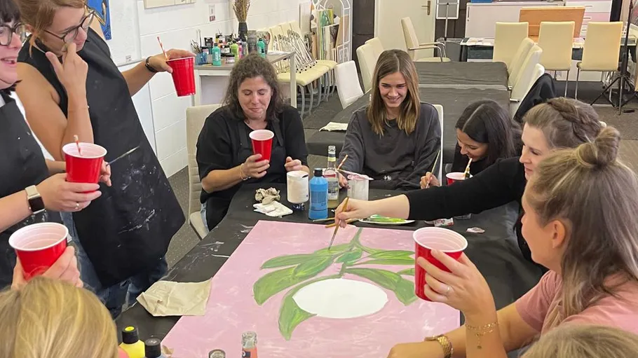 Group painting together on a table in studio.