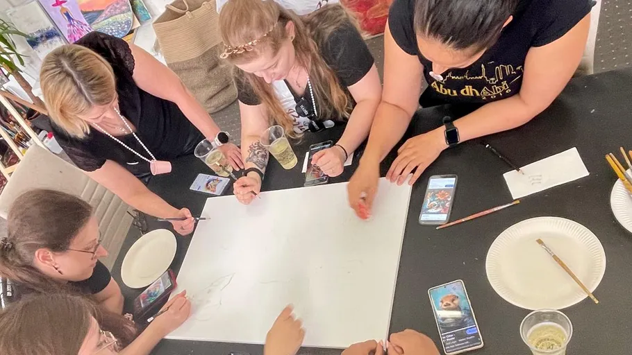 Gruppe zeichnet auf Papier um einen Tisch.