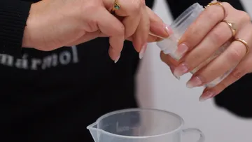 Hände gießen Pulver in einen Messbecher.
