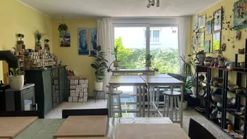 Raum mit Pflanzen, Tischen und Kunstdekoration.