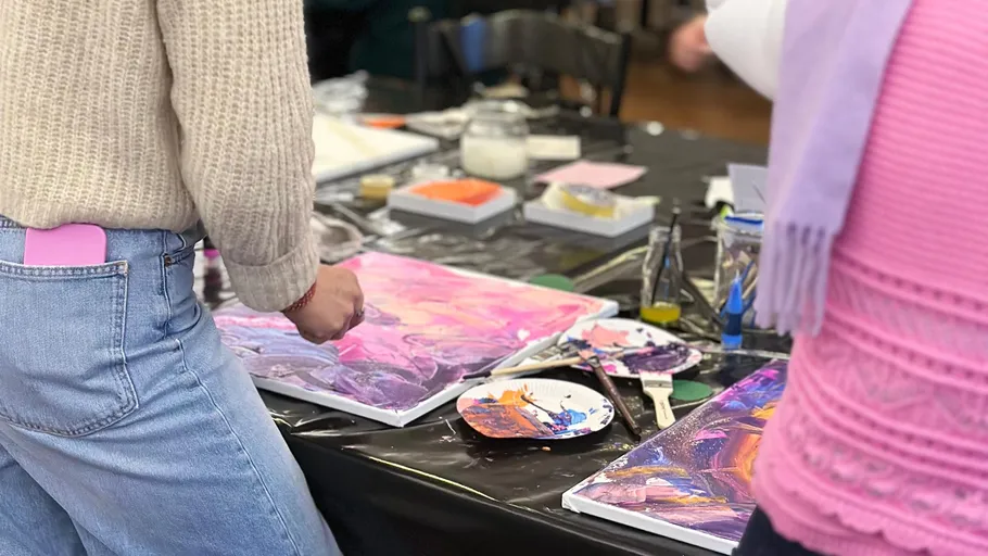 People painting on canvases at a table.