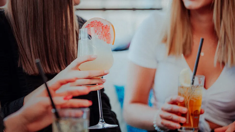 Women holding cocktails in relaxed setting.