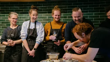Gruppe von Köchen bereitet Essen in Küche zu.