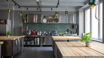 Moderne Küche mit Holztischen und Pflanzen.