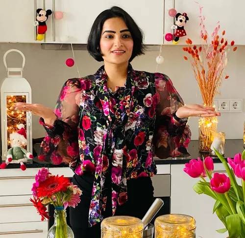Woman in floral blouse, indoor decorated setting.