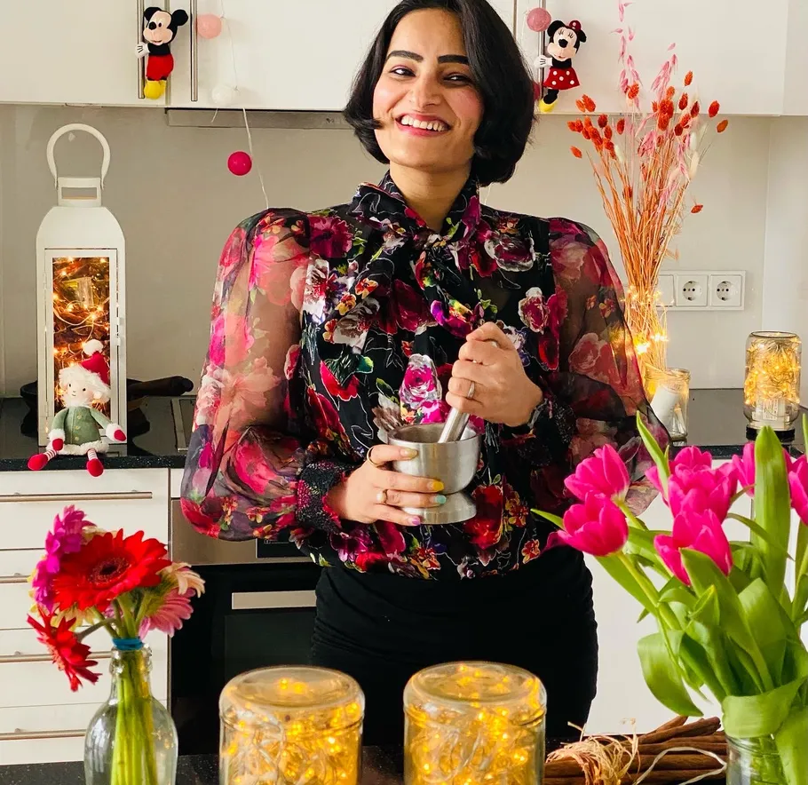 Smiling woman using mortar and pestle in kitchen.